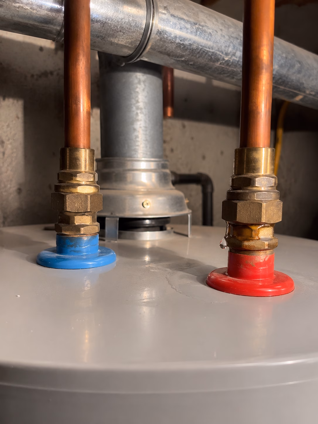Water dripping at a corroded pipe connection on top of a water heater